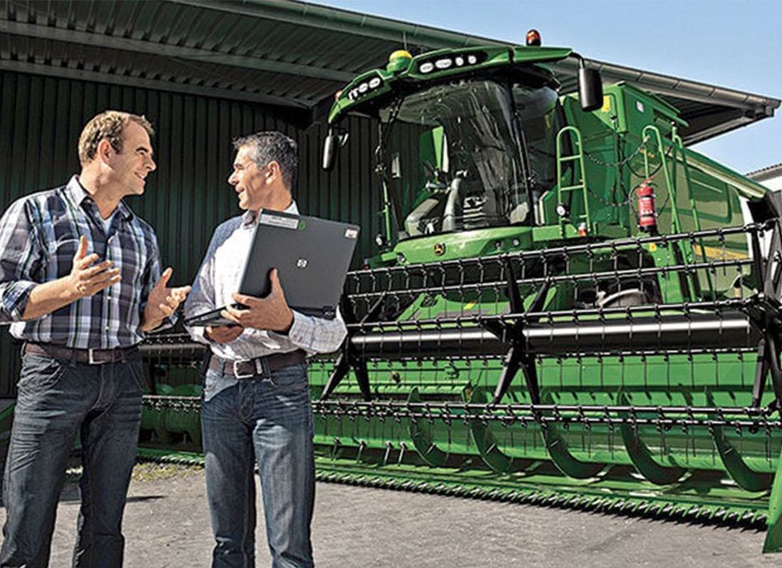 Agribusiness Insurance - Farm Businessmen Negotiating the Sale of a Large Piece of Agriculture Business Equipment on a Sunny Day